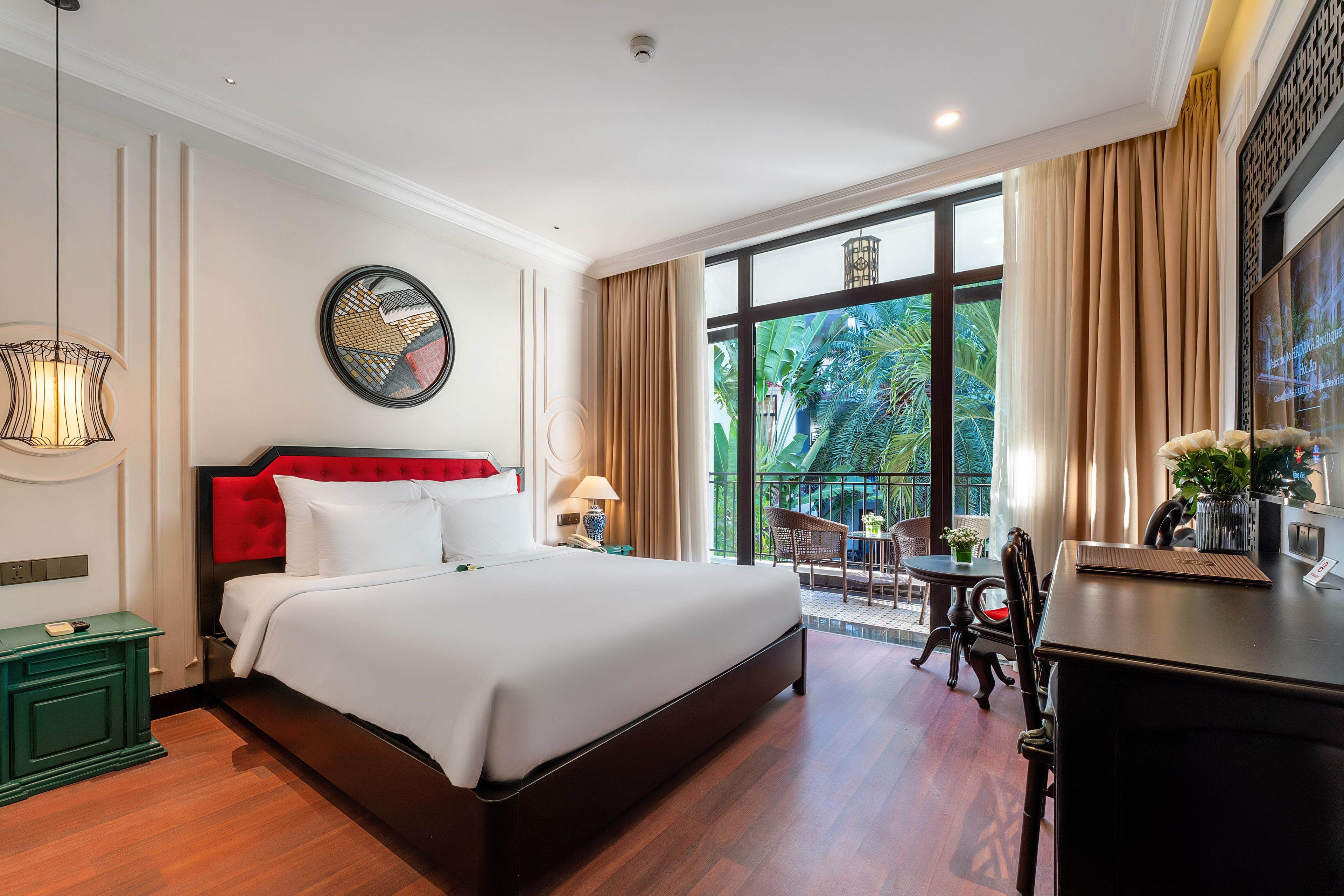 Bright and modern hotel room featuring a queen-sized bed, wooden flooring, and large windows with views of an outdoor pool area. The room is tastefully decorated with warm colors and elegant furnishings