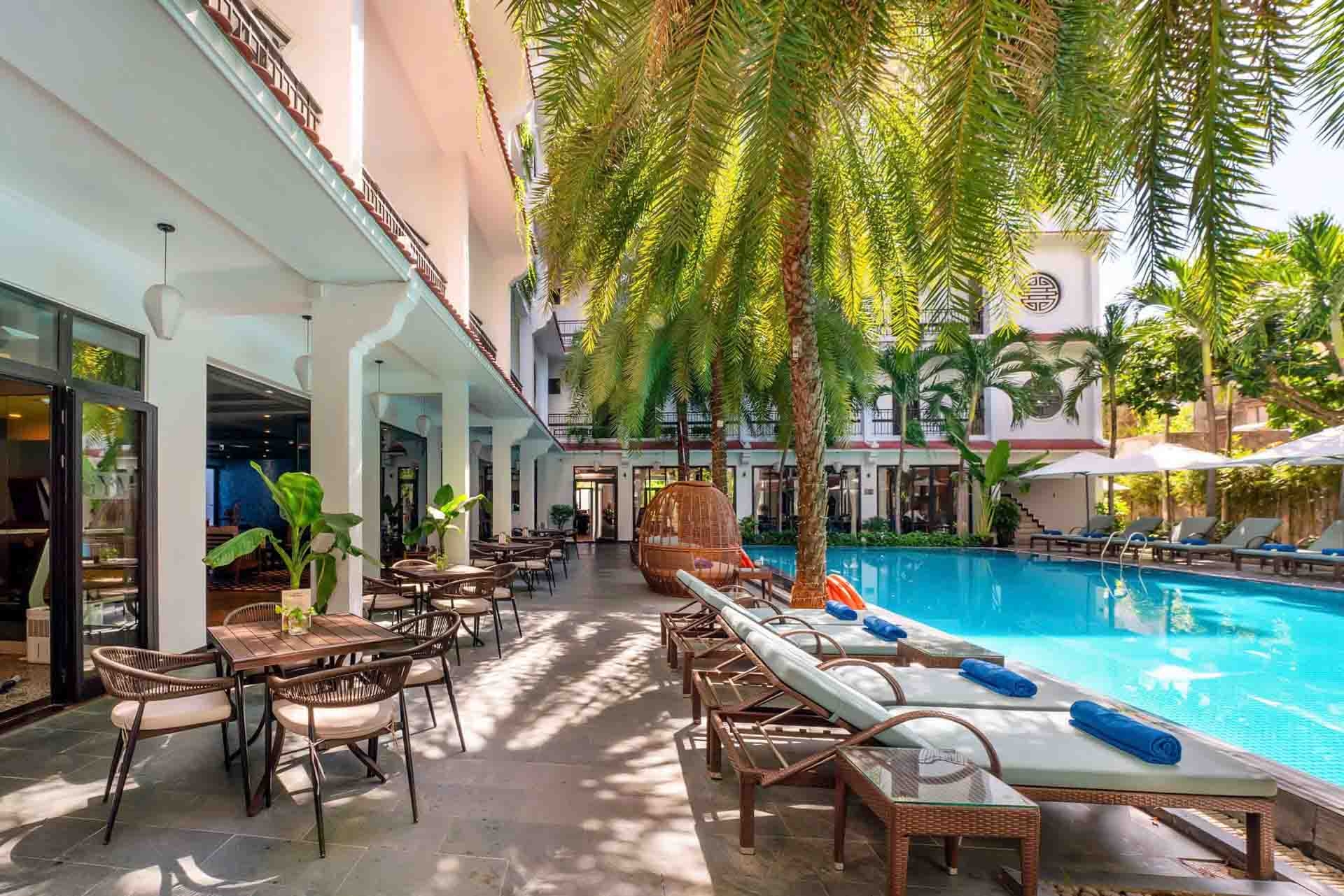 view of tropical pool area featuring lounge chairs and lush palm trees
